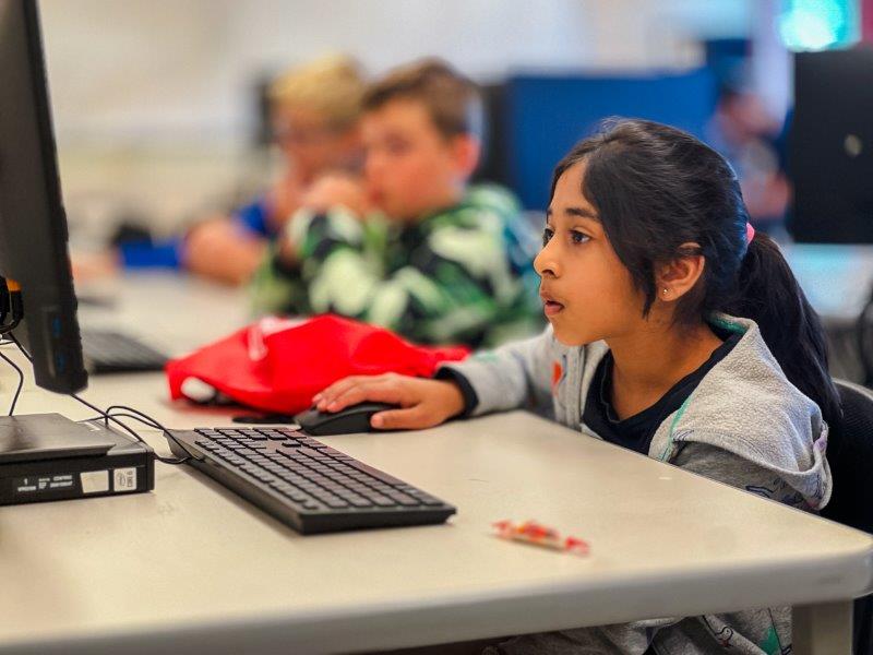 a student is sitting at a table operating a computer